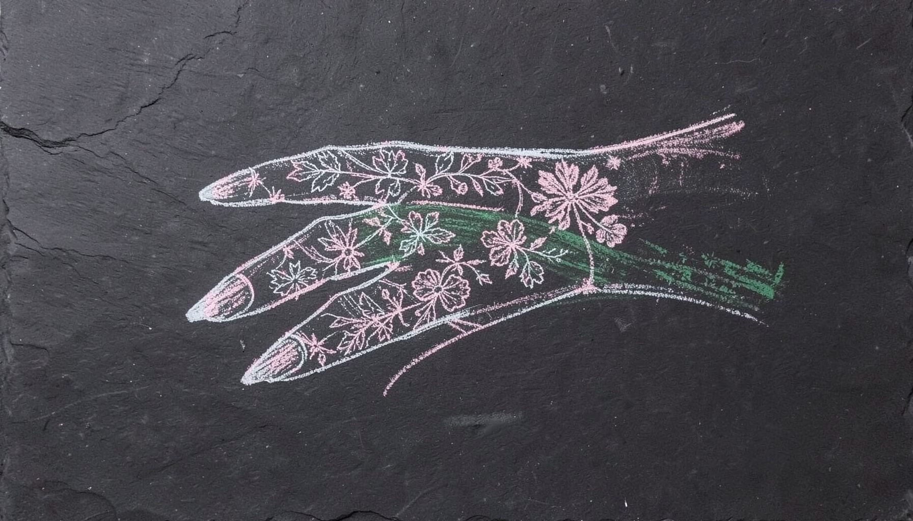A chalk drawing on a dark slate board of an elegant hand with long nails featuring intricate floral stamping patterns, drawn in white and pale pink chalk with delicate linework.