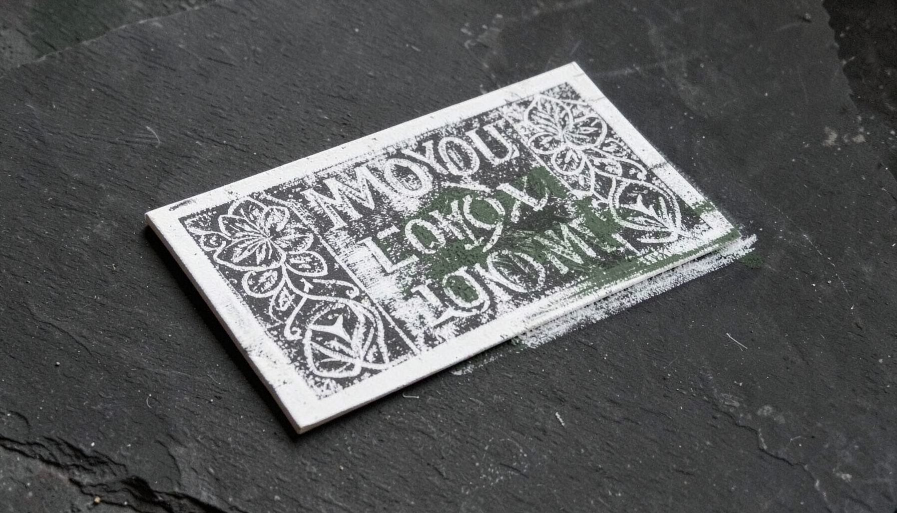 A rectangular MoYou London stamping plate with etched floral and geometric designs, held at an angle to catch the light.